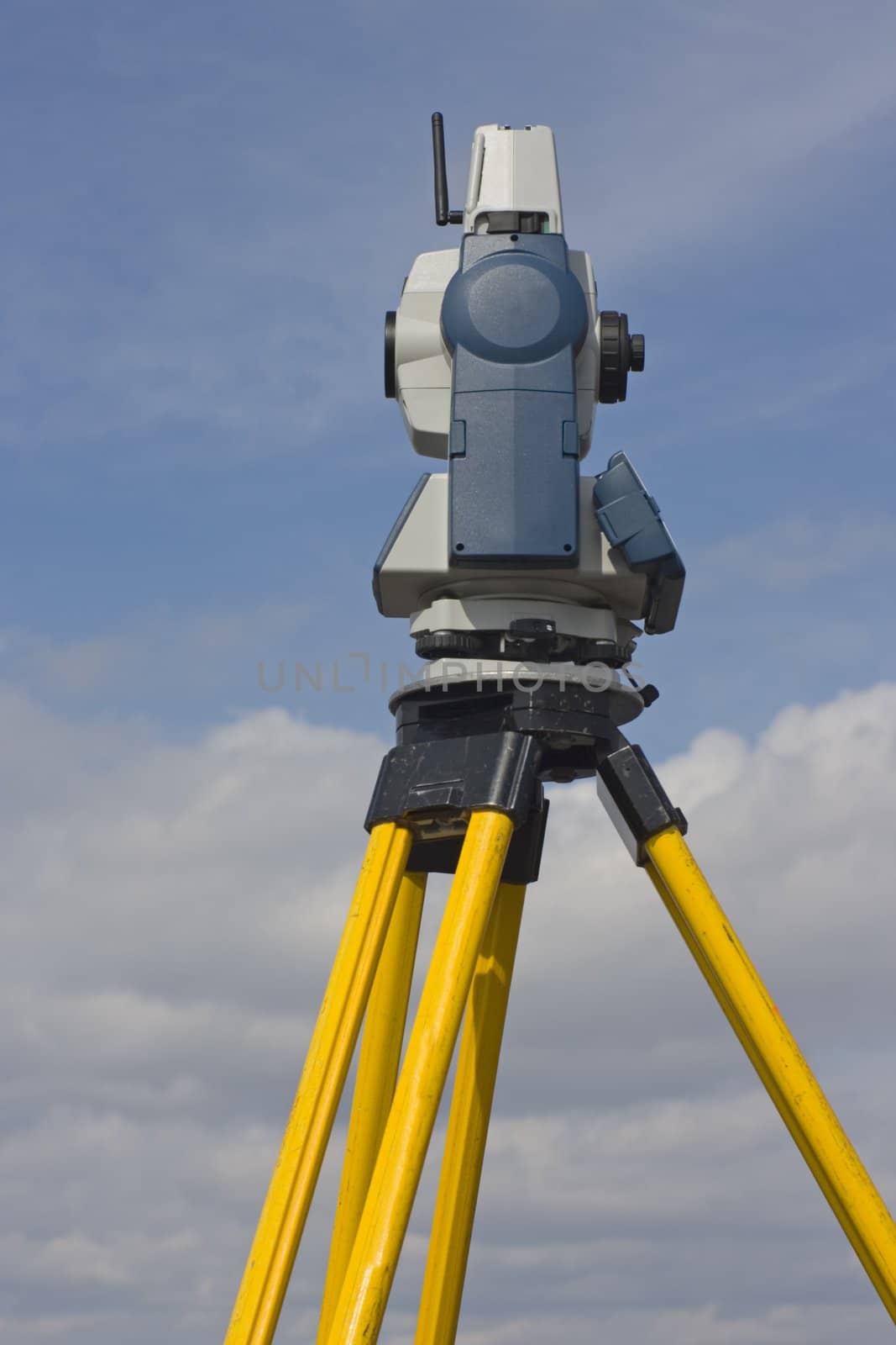 Side of theodolite against cloudy sky.