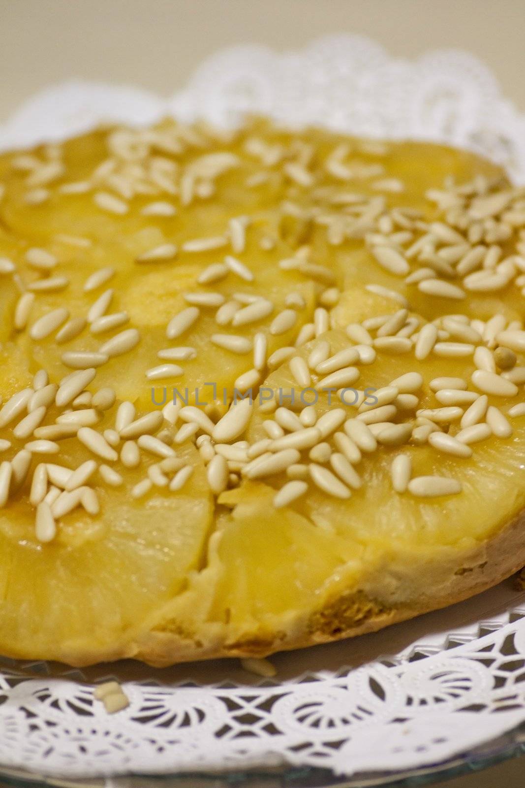 Close view of a homemade pineapple cake decorated with pine nuts.