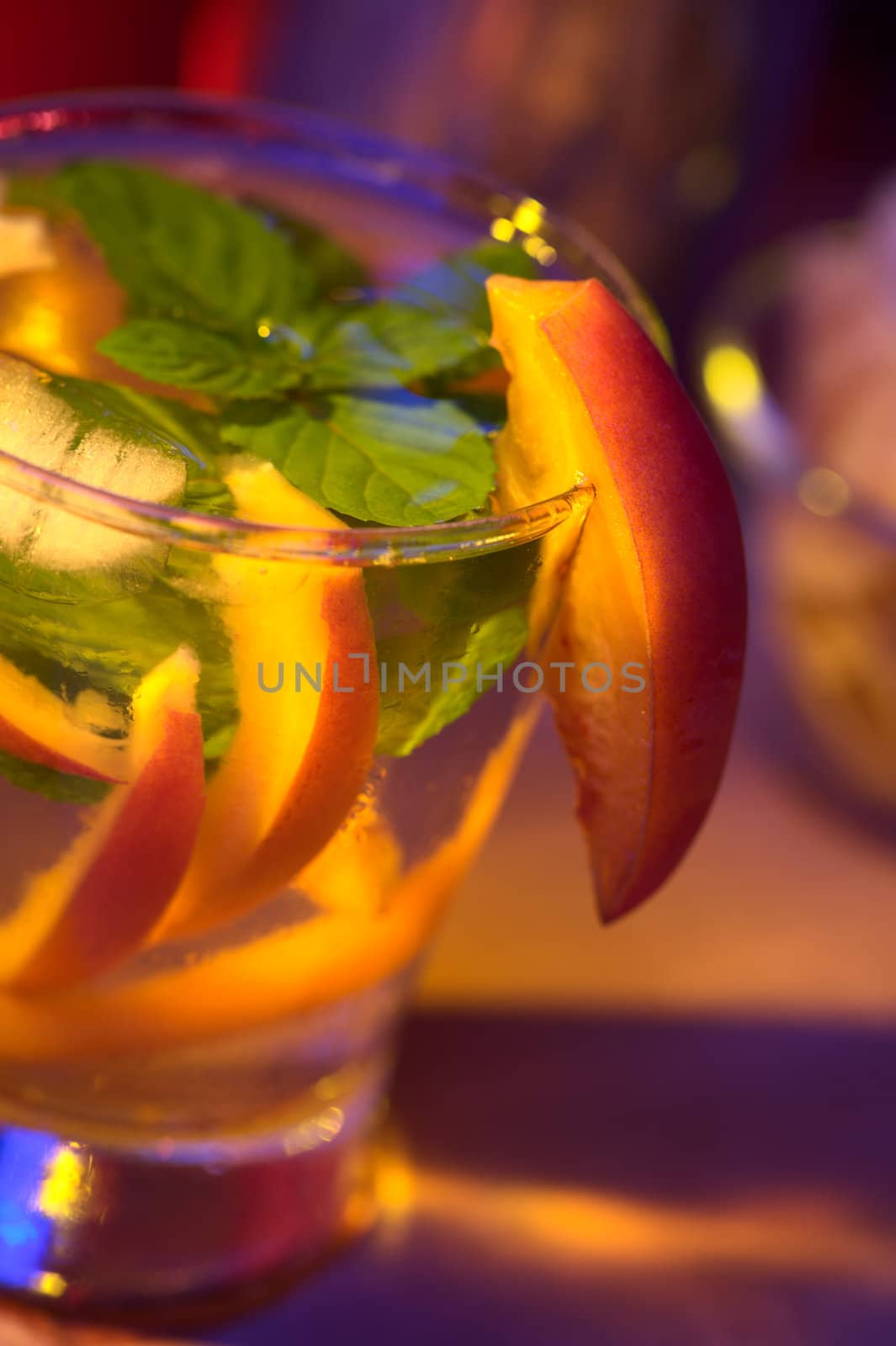 Tamarillo cocktail (Very Shallow Depth of Field, Focus on the front edge of the mint leaf and the front of the tamarillo garnish at the height of the glass rim)