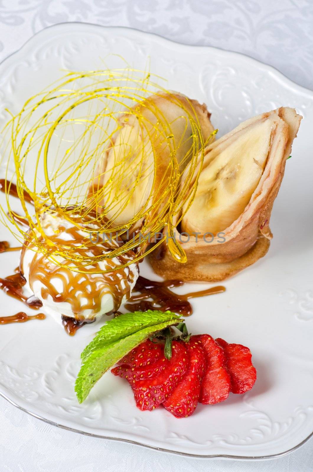 Dessert of pancake with banana, ice-cream, caramel, strawberry and mint