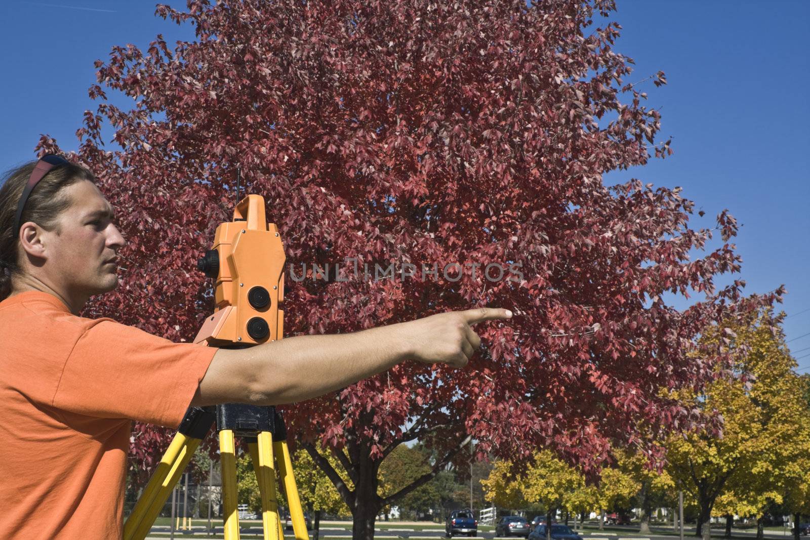 Surveyor with theodolite during colorful fall