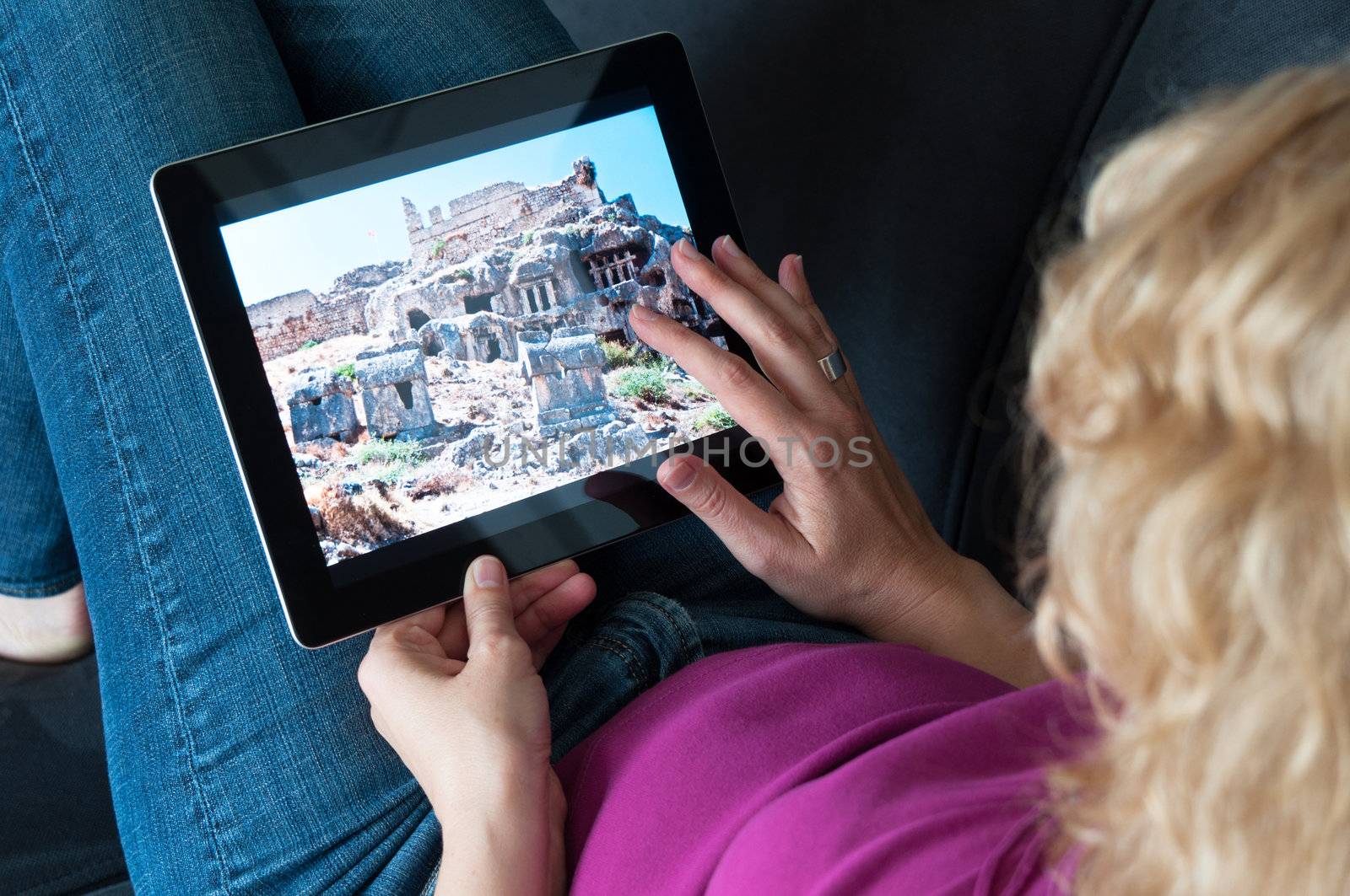 Middle-aged woman sitting comfortably on a sofa and checking a digital tablet pc