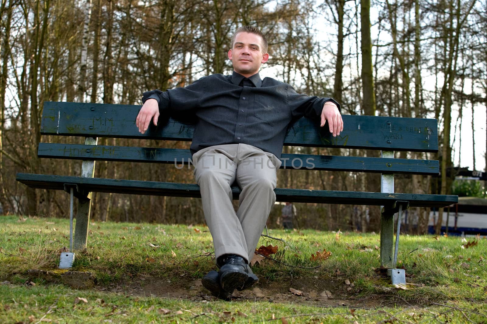 Young man is sitting on a bench in a park