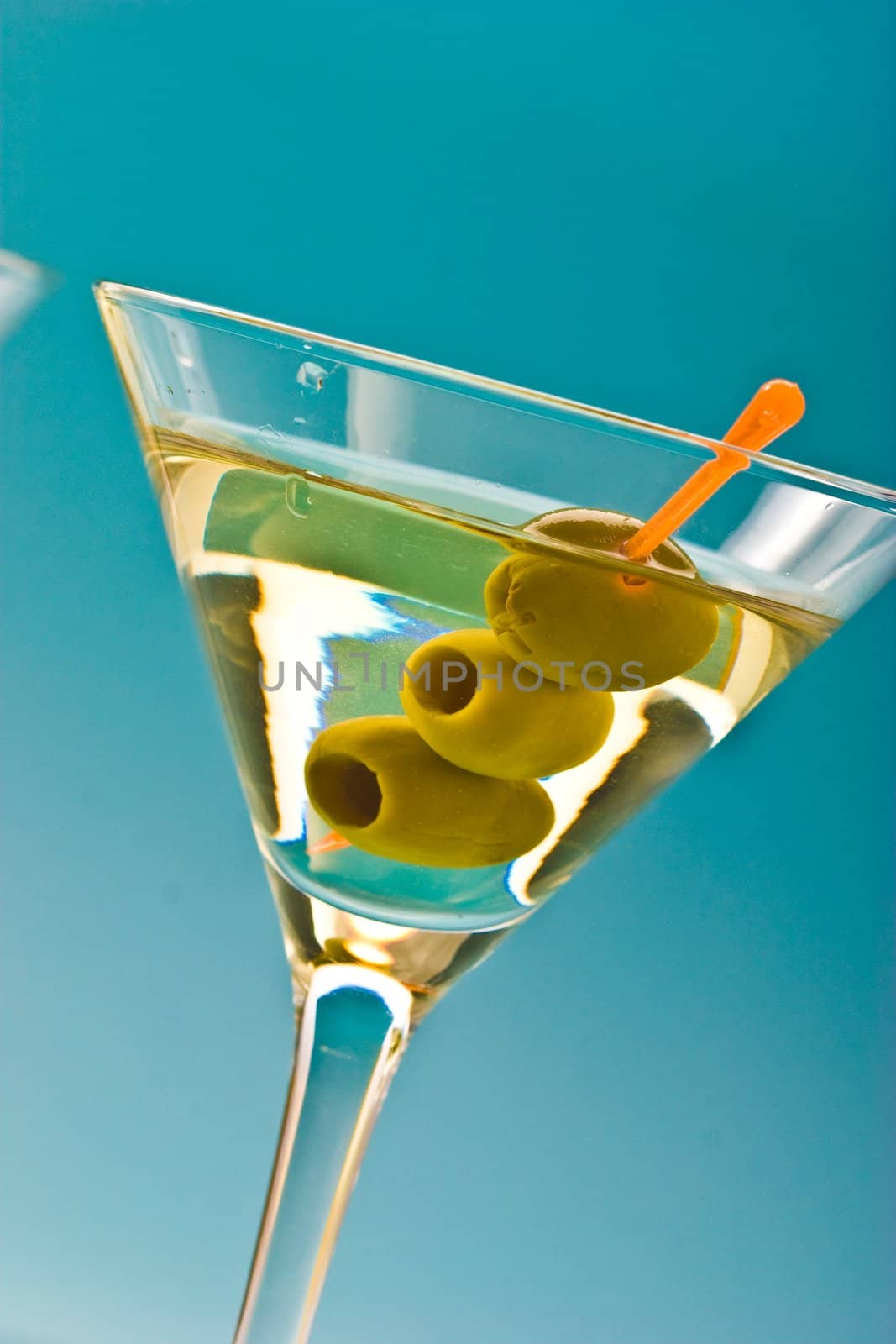 one bocal of martini with olive over blue