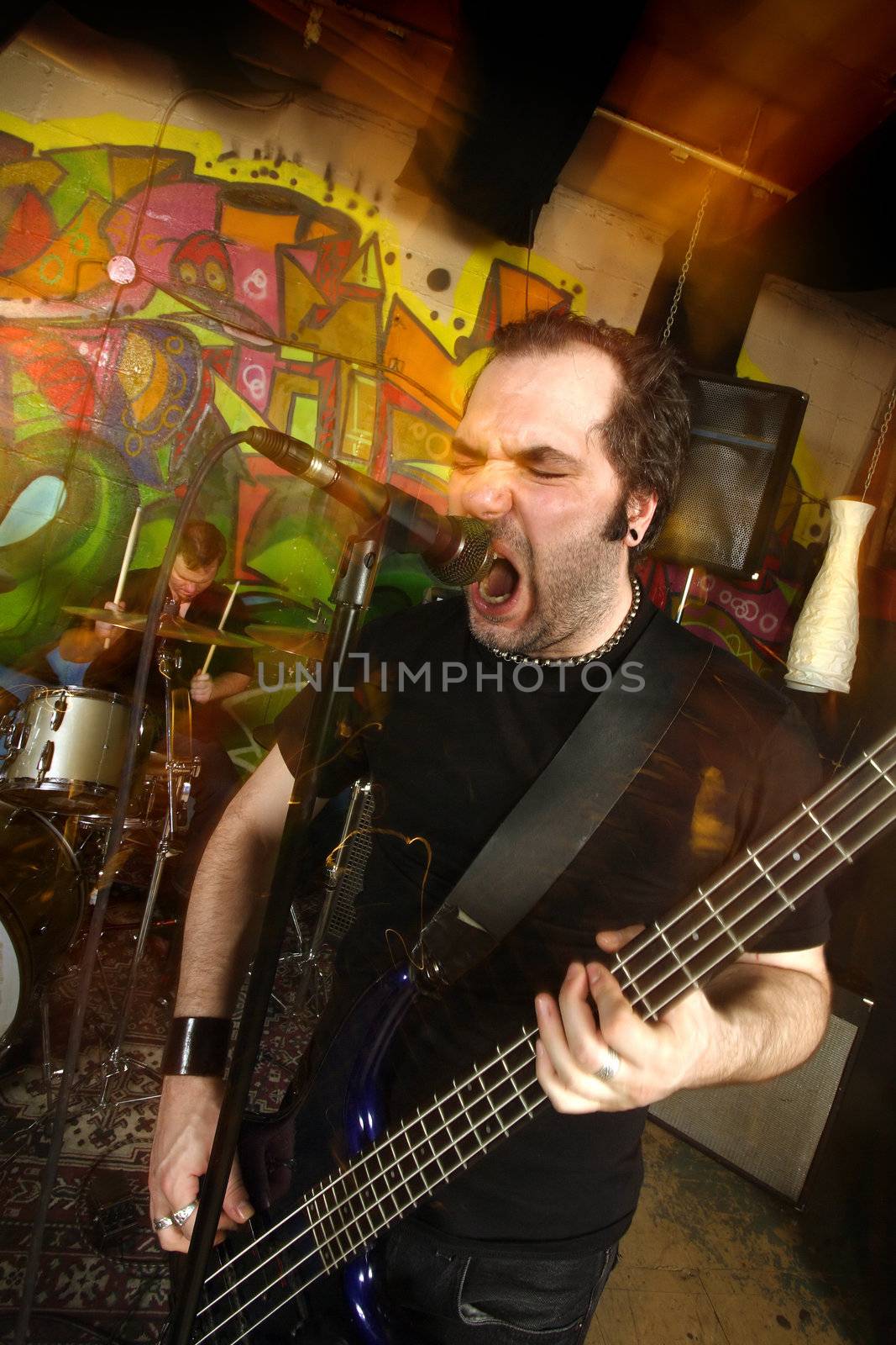 Metal singer cussing into the microphone.  Shot with strobes and slow shutter speed to create lighting atmosphere and blur effects.
