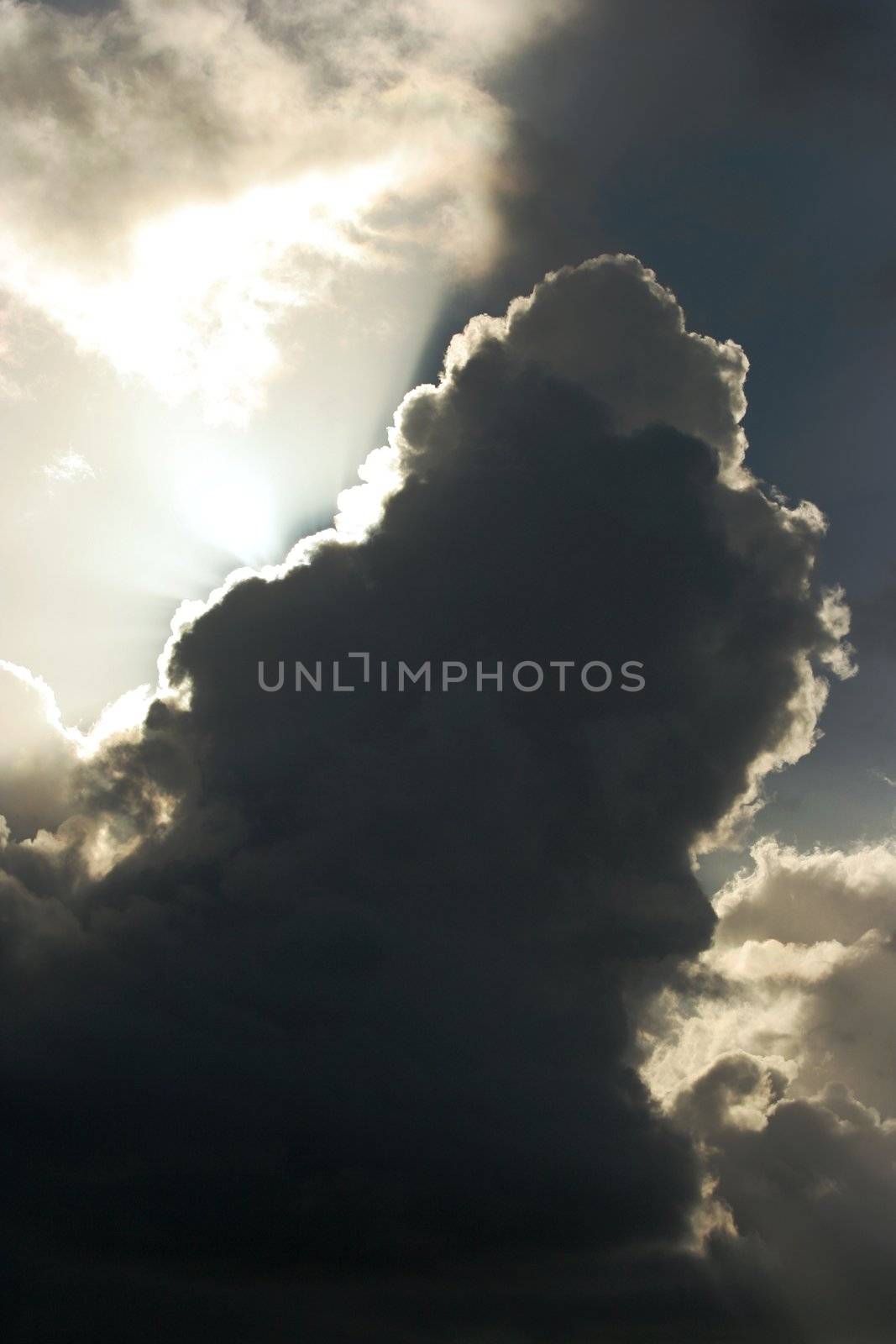 Billowing clouds and suns rays shining behind