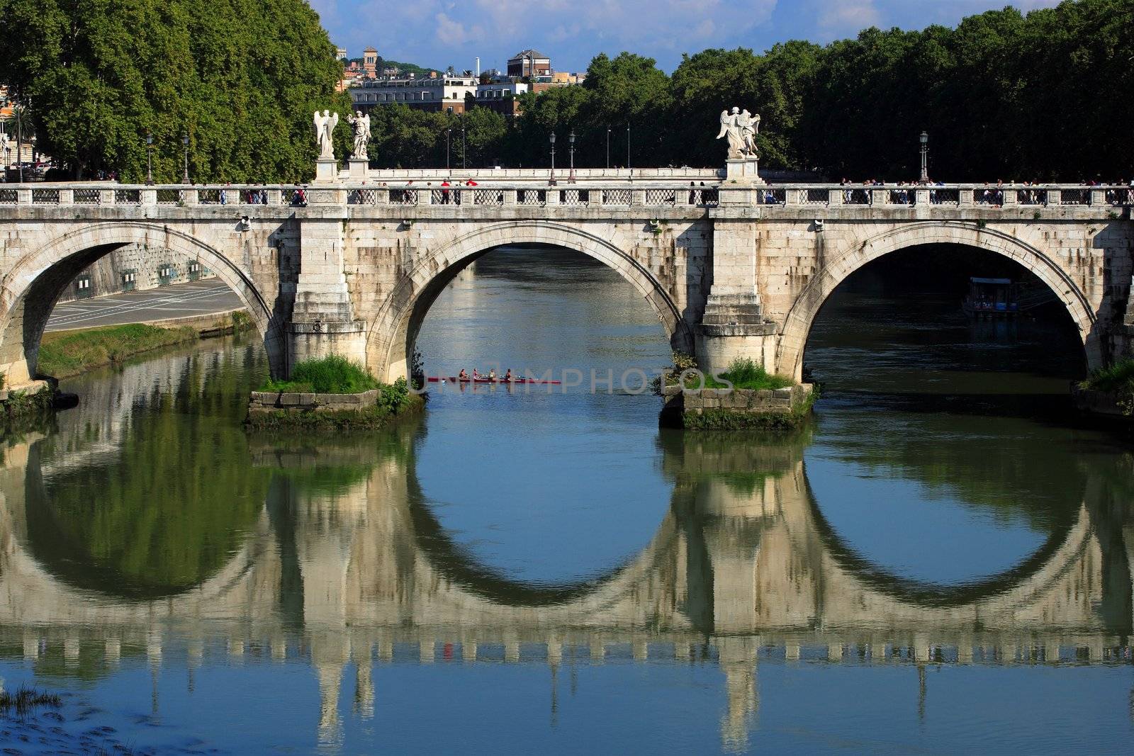 Old bridge in Rome, Italy - with a group of rowers passing underneath.
