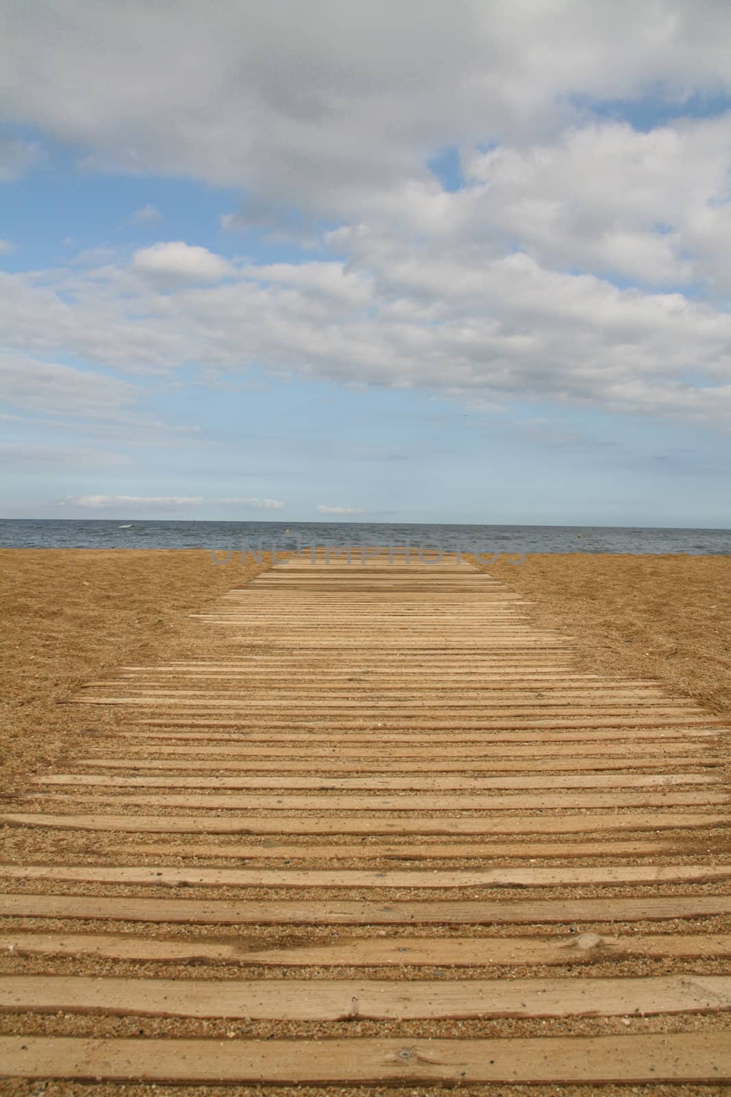 wooden boards path on the sand on a beach, blue horizon