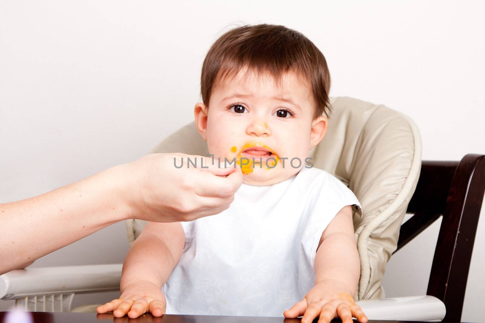 Cute baby infant boy girl expresses dislike disgust for food fed by spoon.