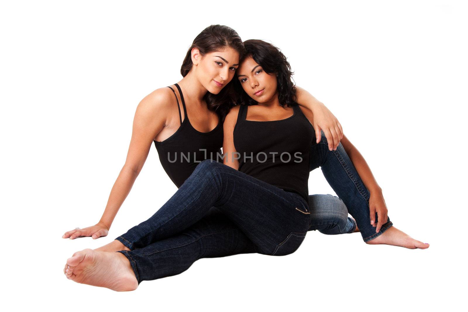 Beautiful female fashion couple sitting together wearing blue denim jeans and black tank top, isolated.