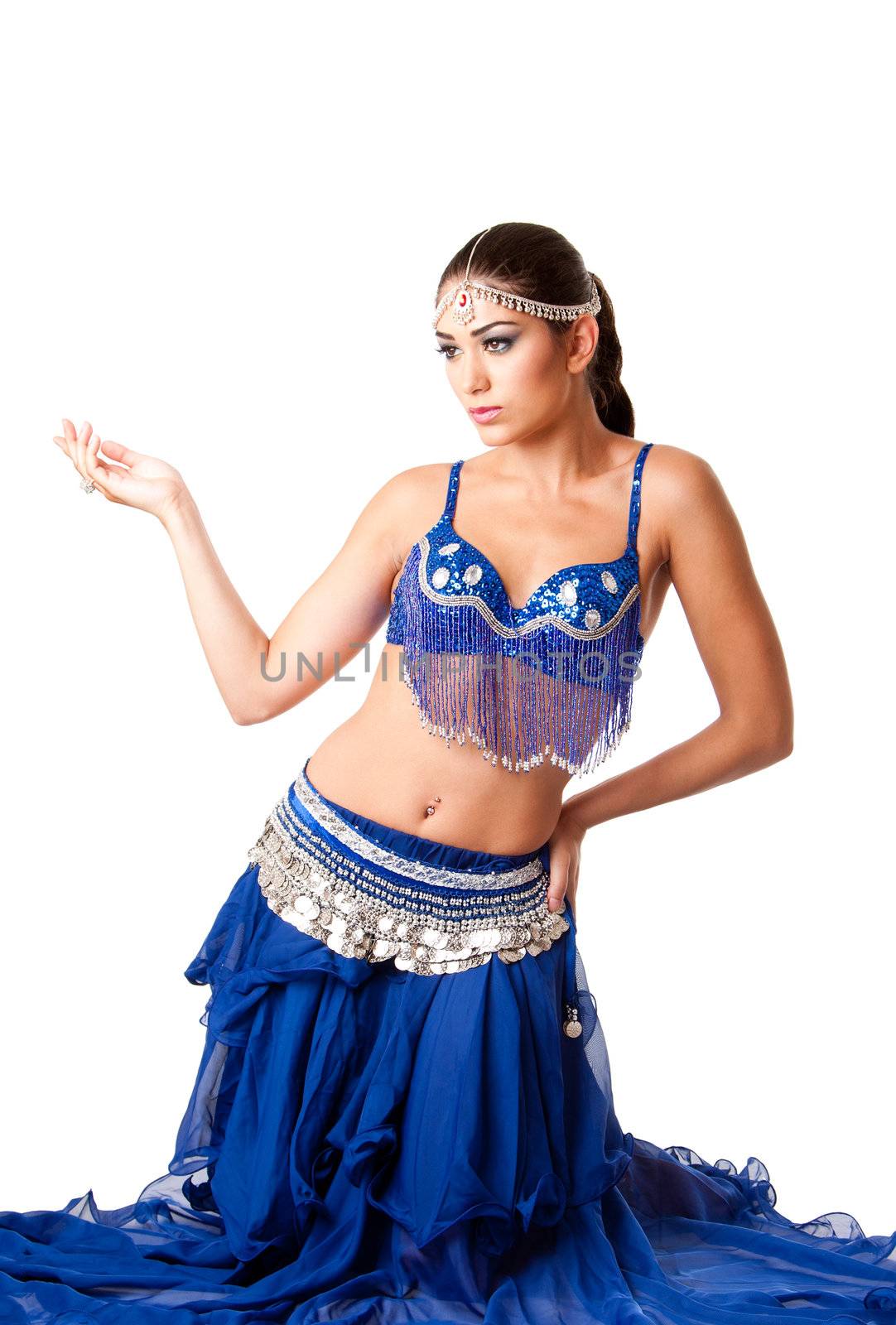 Beautiful Israeli Egyptian Lebanese Middle Eastern fashion belly dancer performer in blue skirt and bra sitting on knees, isolated.
