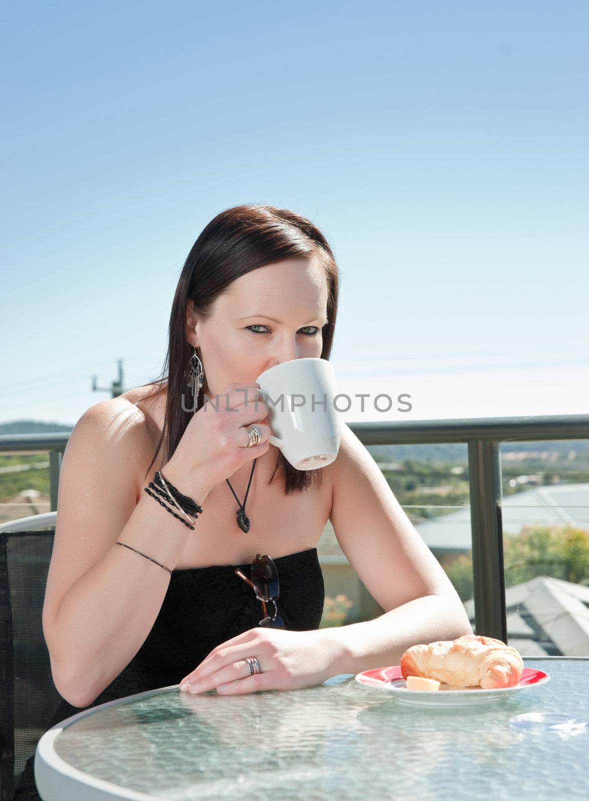 young woman having breakfast crossiant and coffee in cafe