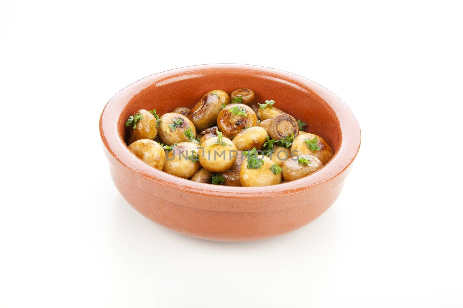Marinated mushrooms in earthenware bowl isolated on white background.