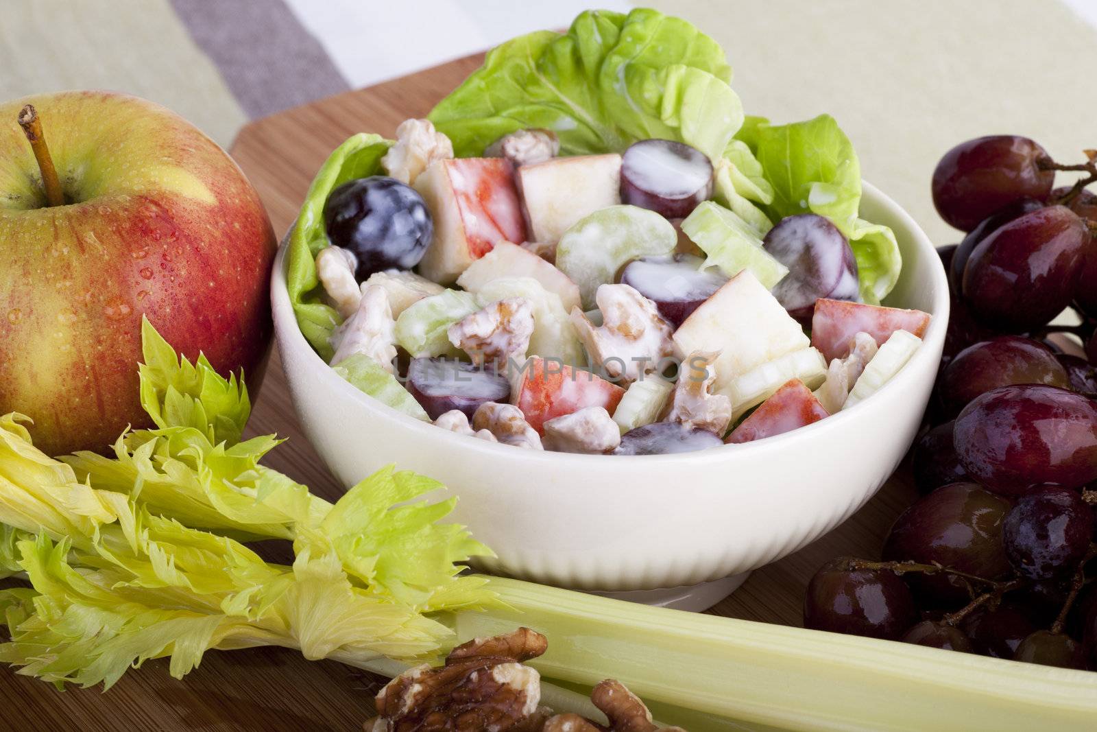 Bowl of Waldorf salad surrounded by ingredients for salad.
