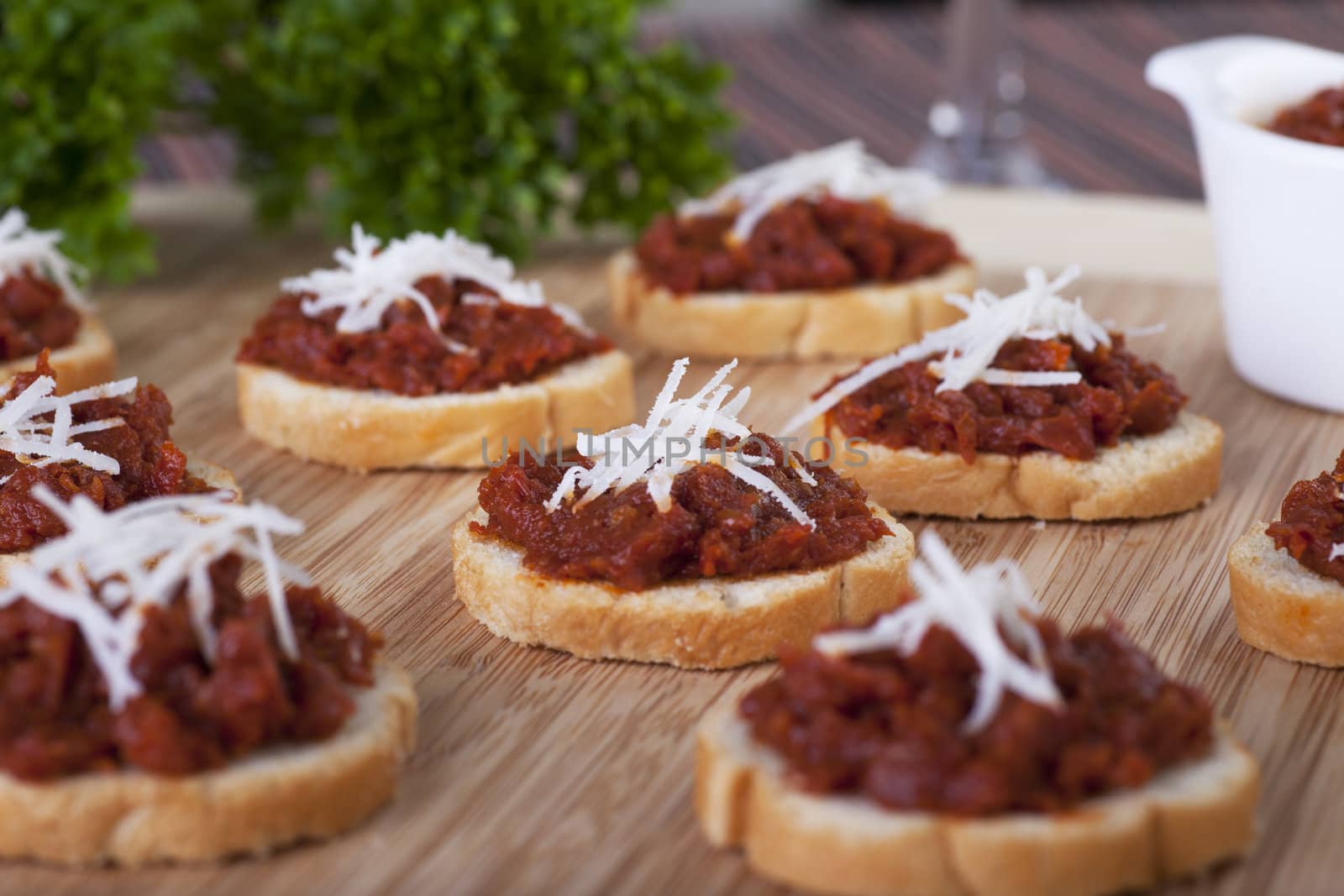 Fresh homemade sun dried tomato tapenade on toasted baguette topped with fresh grated cheese.