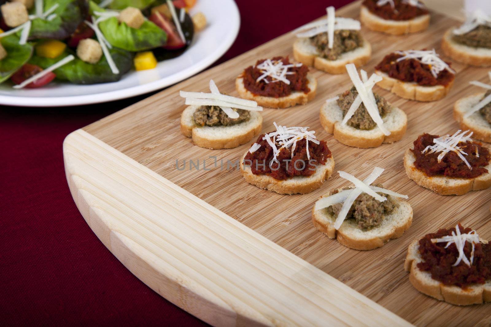 Fresh homemade sun dried tomato tapenade on toasted baguette topped with fresh grated cheese and a side salad.