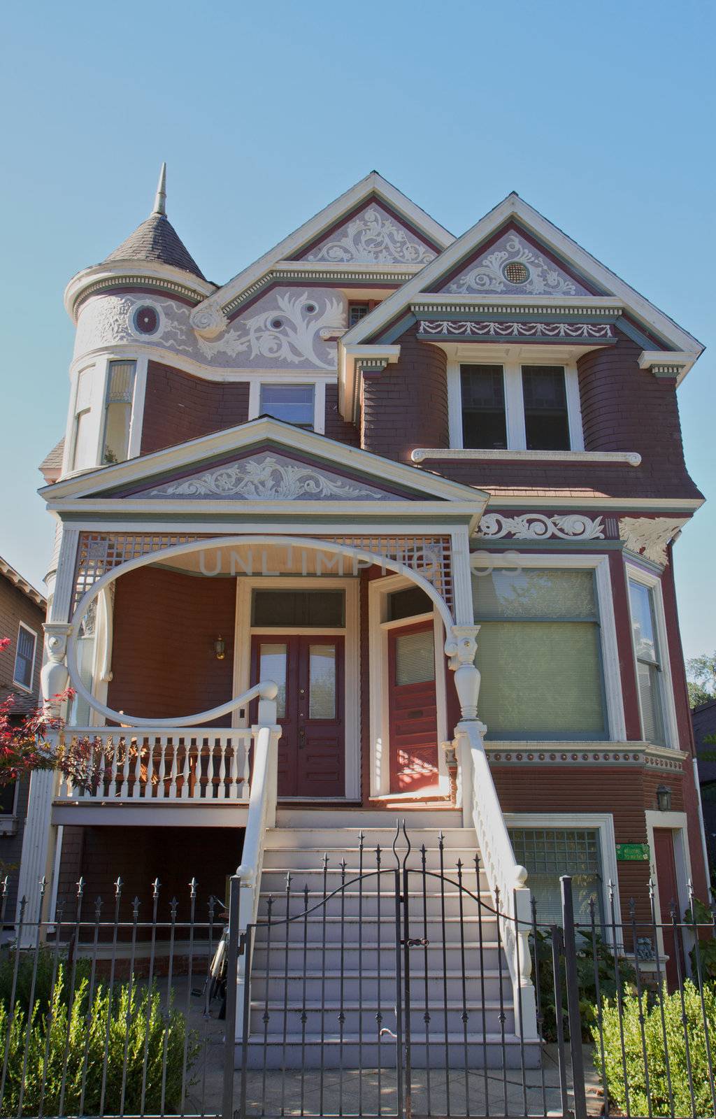 Looking up at a sun lit magneta colored victorian house