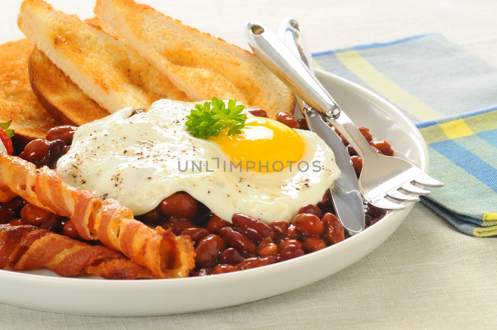 Fried egg with bacon, toast and beans.