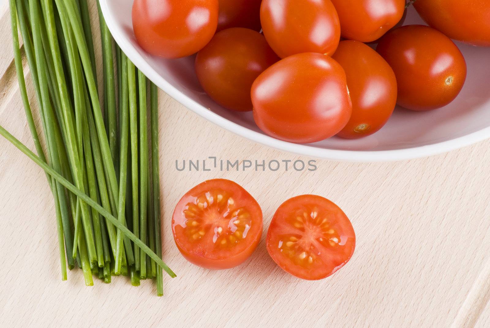 Fresh cherry tomatoes and chives on cutting board