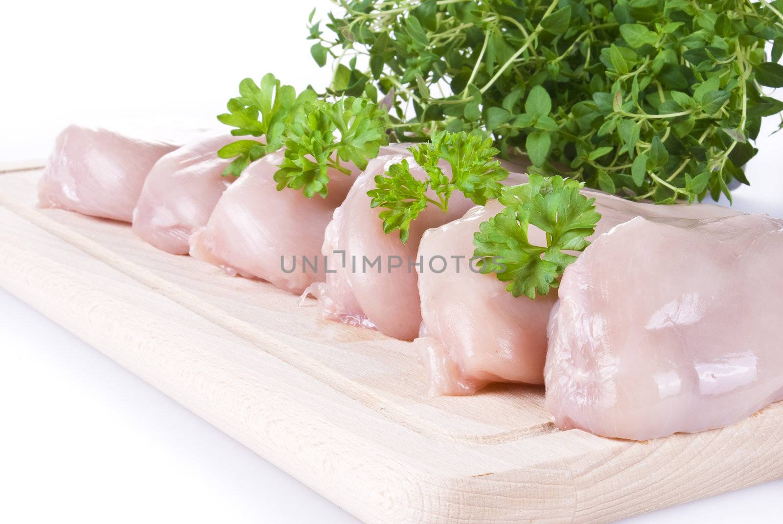 Raw chicken breasts on chopping board with herbs