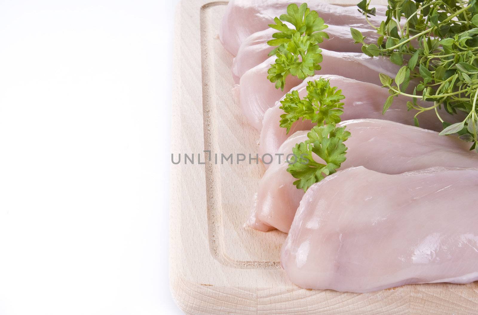 Raw chicken breasts on chopping board with herbs