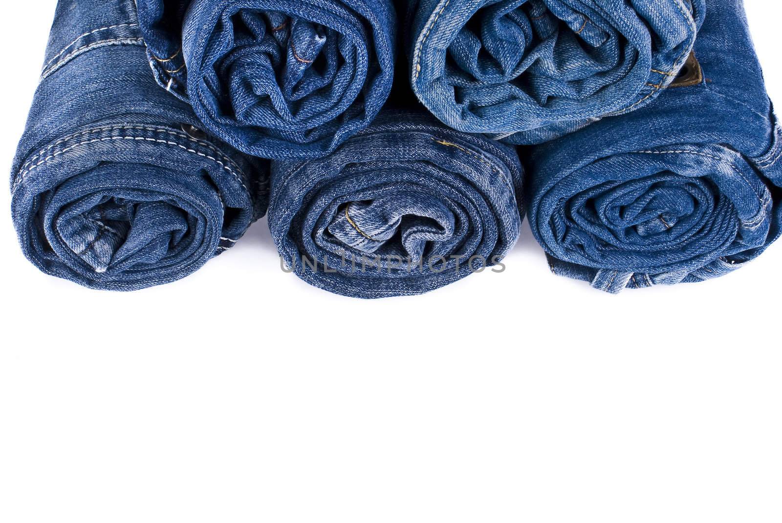 stack of various shades of blue jeans over white background