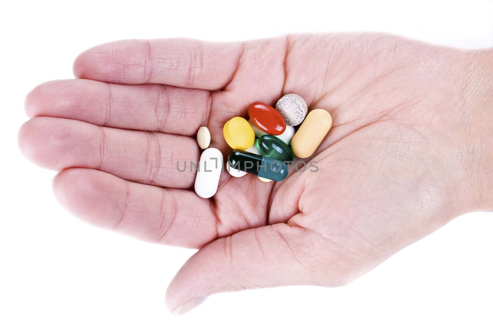 hand with various pills over white background