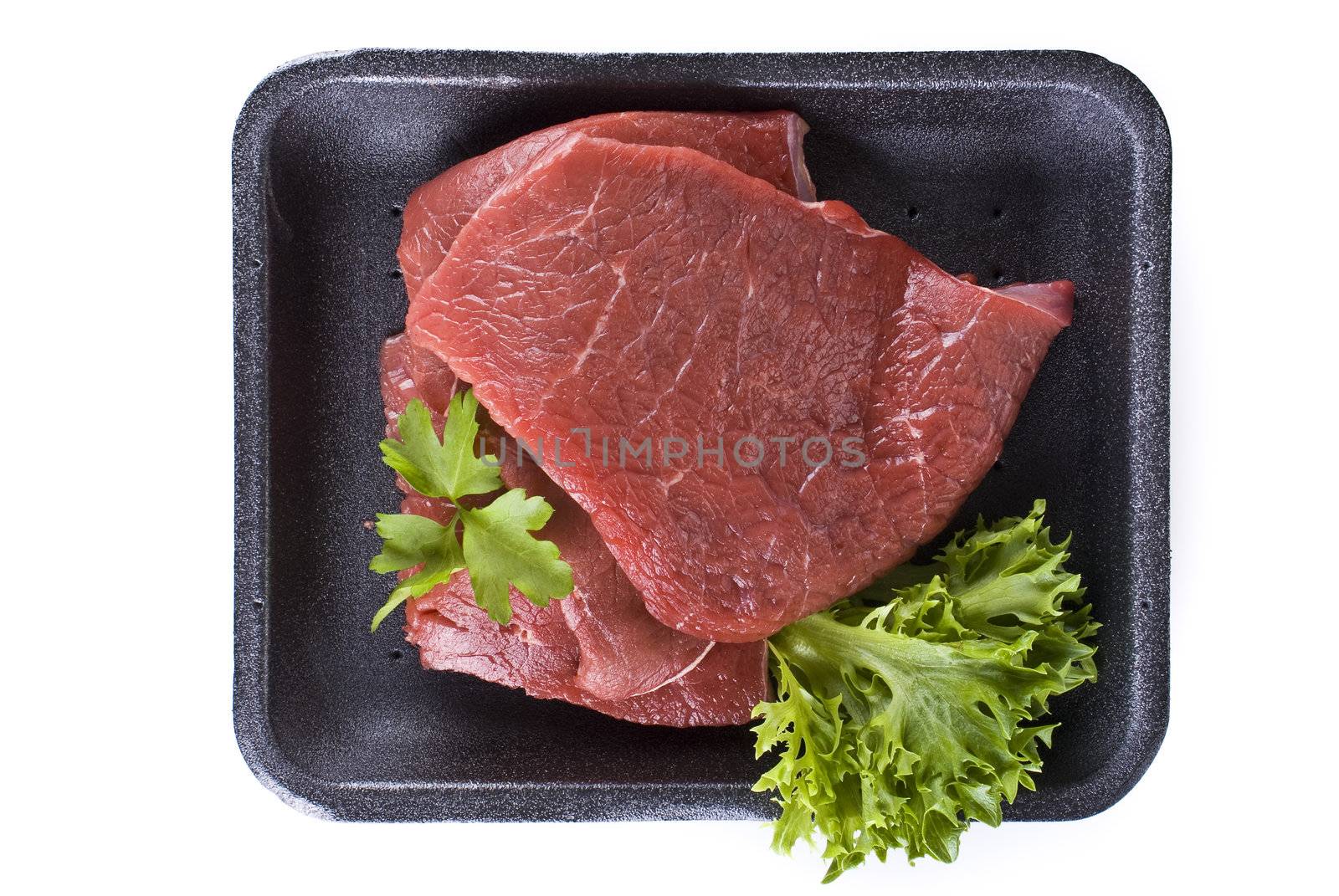 Raw beef frying steak in black tray  isolated over white background