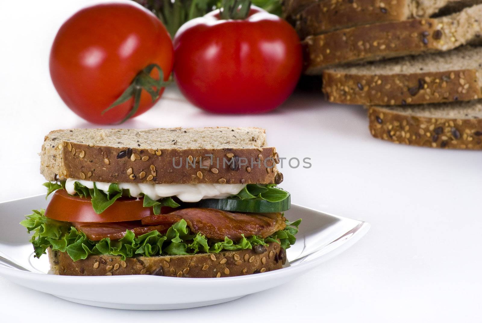 Freshly made bacon sandwich with sliced bread and tomatoes on the background