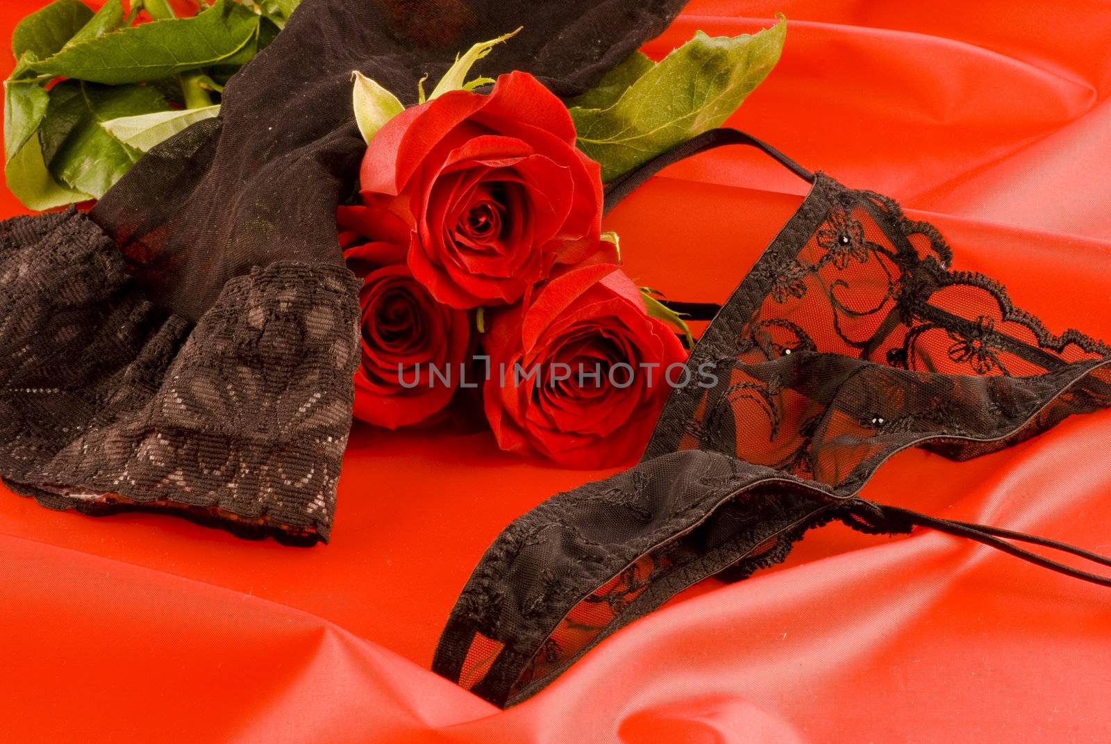 Black strings and stockings with red roses on red background