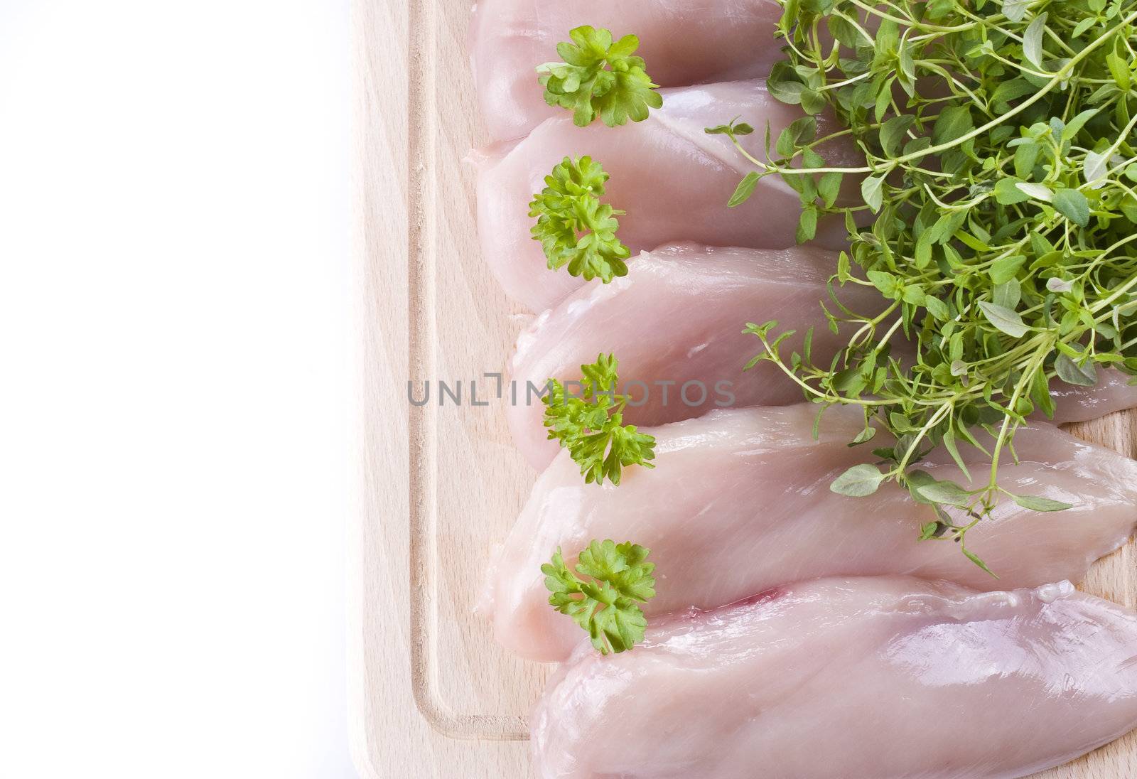 Raw chicken breasts on chopping board with herbs