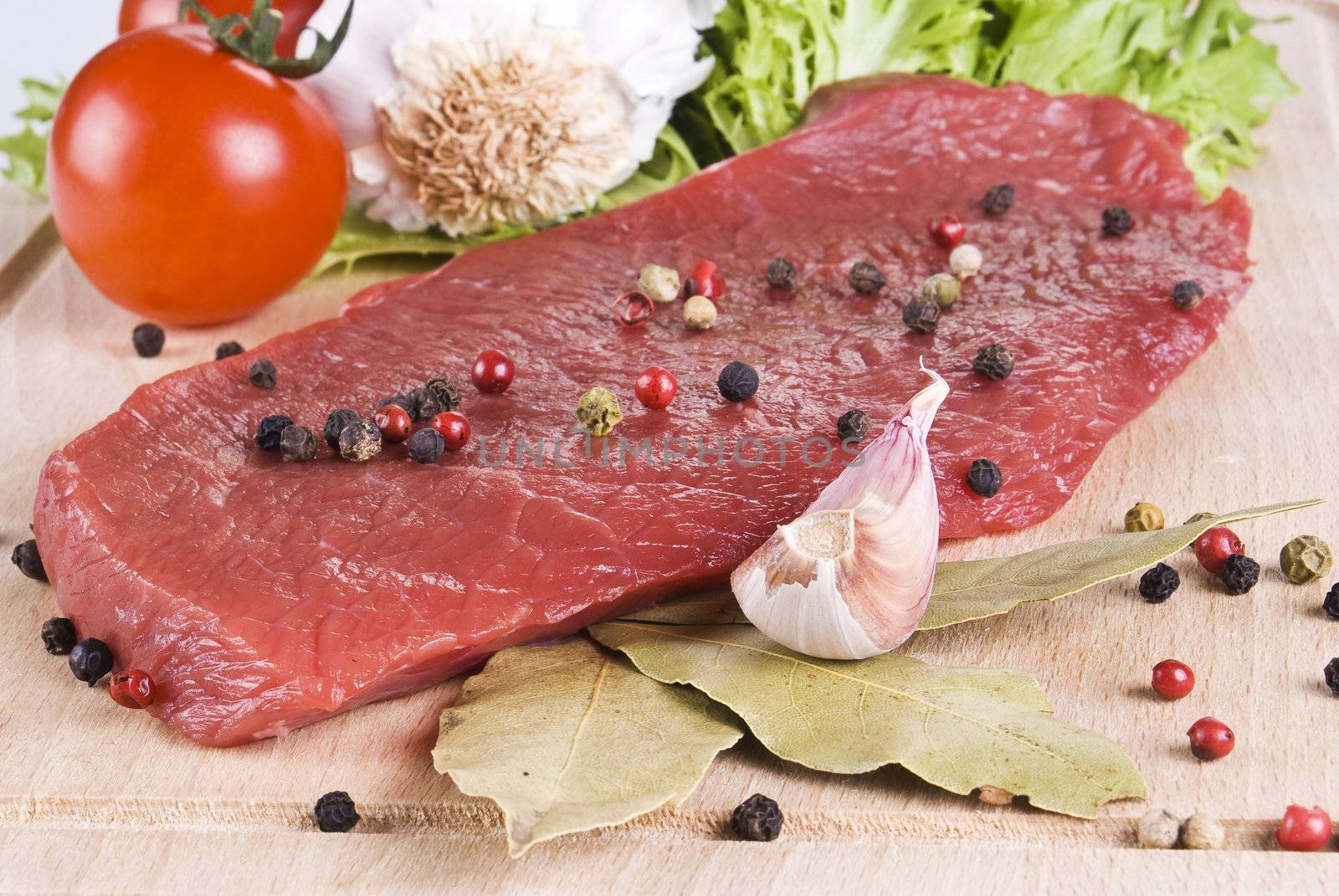 Raw beef frying steak on chopping board with vegetables 