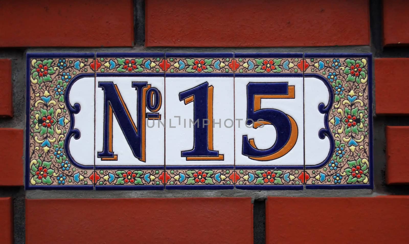 House number tile plaque with floral ornament. 
Over bricks