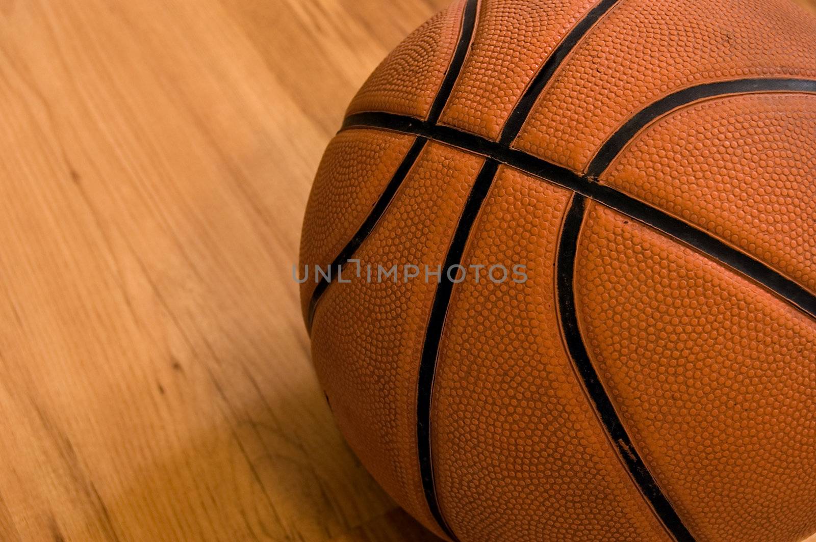 Basketball over wooden floor. Close up.