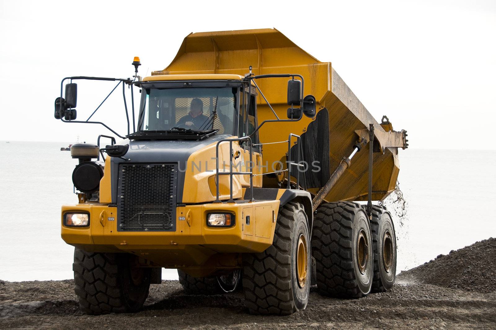 A yellow dump truck unloading gravels