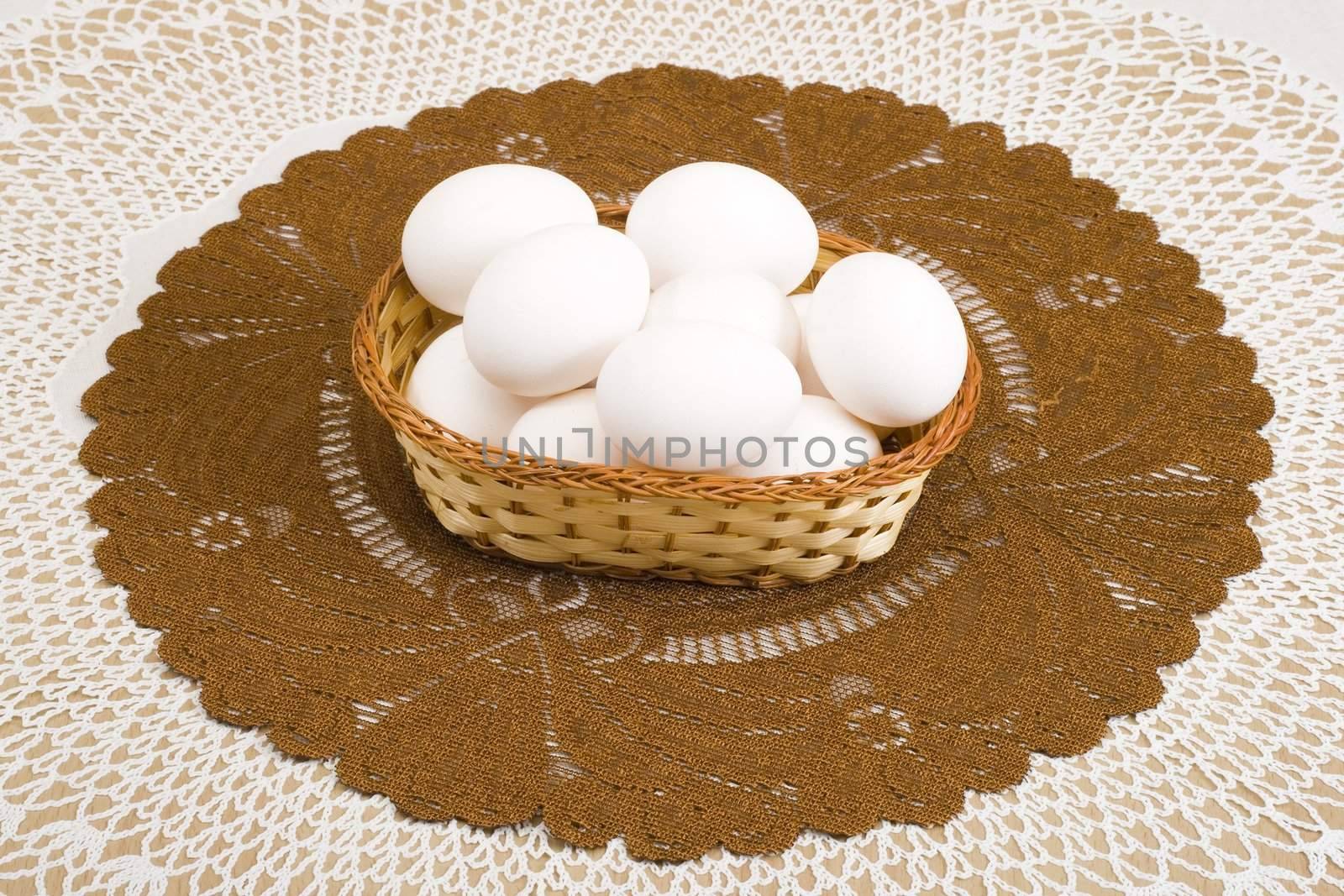 a basket of white eggs on the brown tablecloth