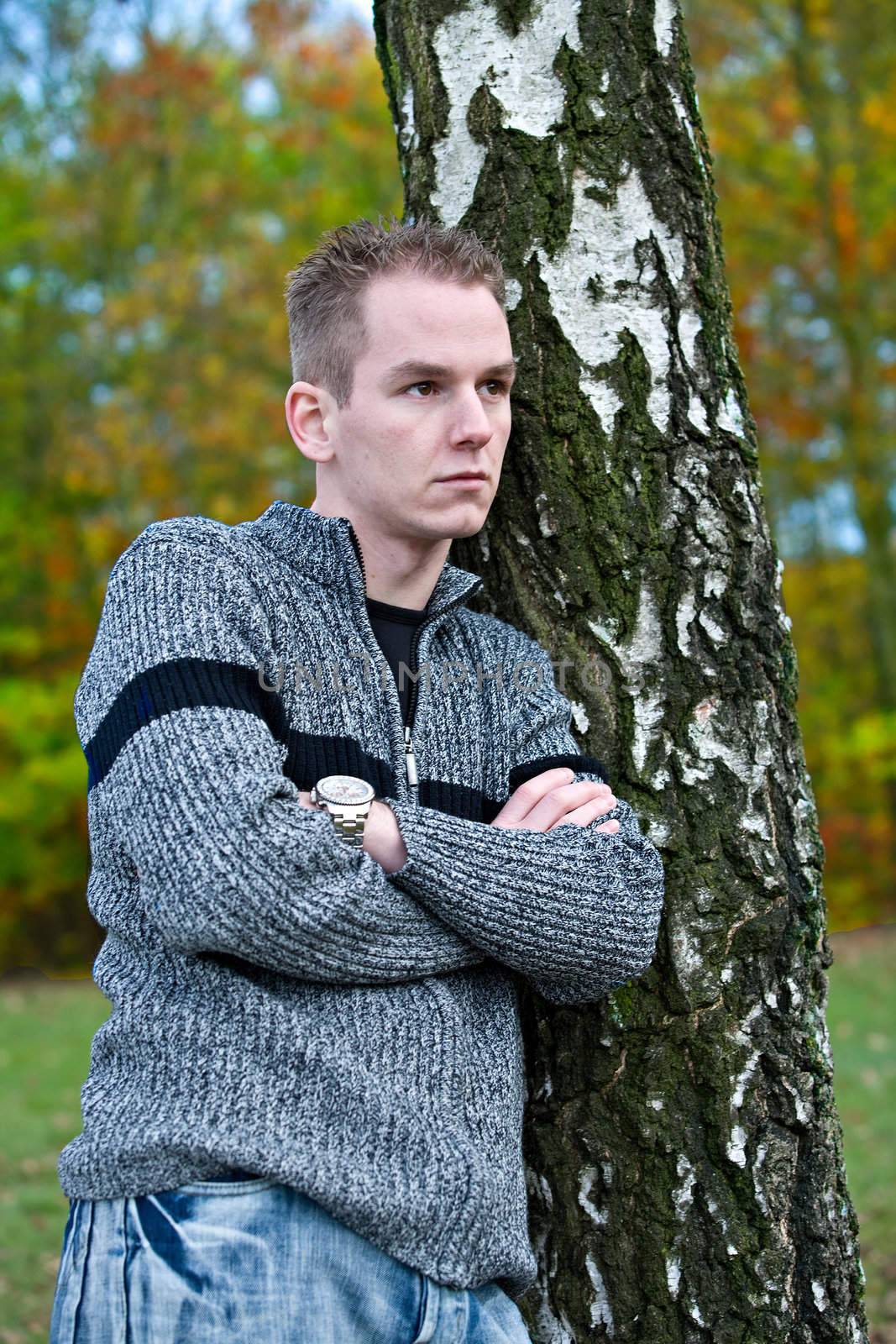 Boy is waiting befront of a tree