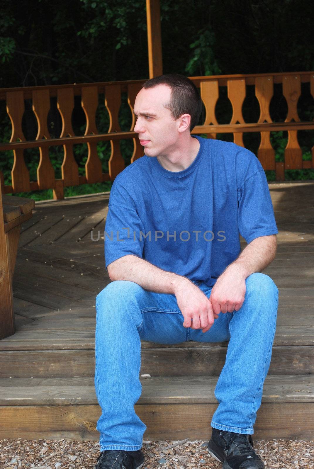 A young man sitting on a wooden step.