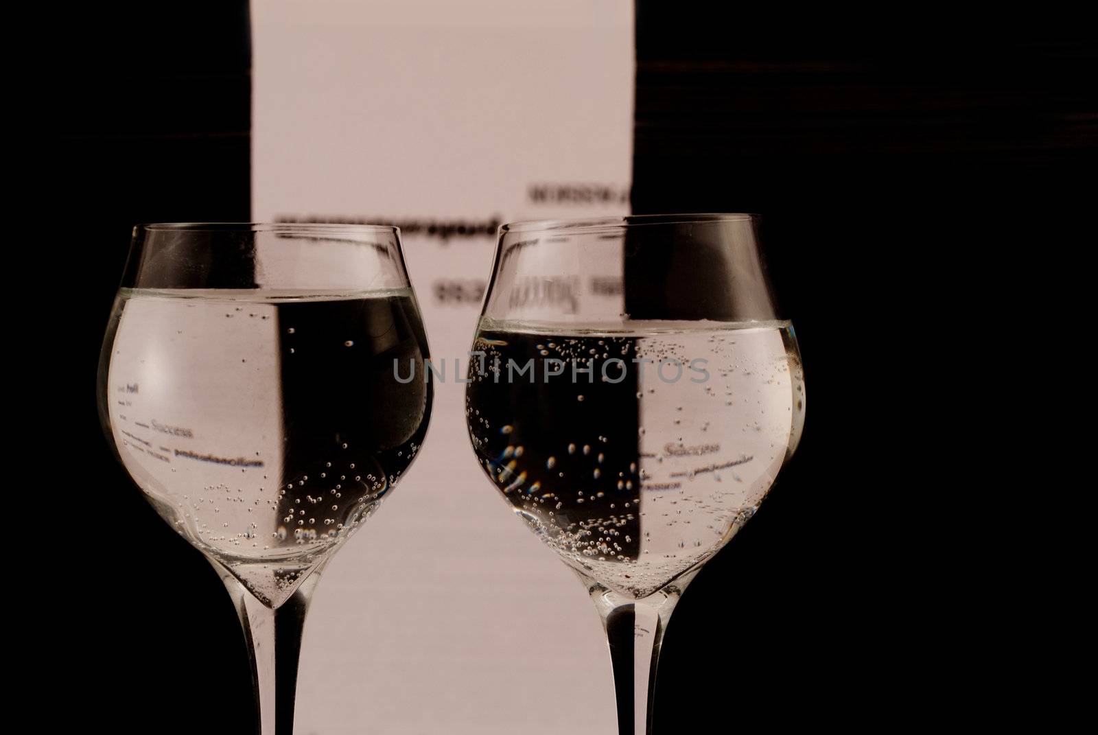 Two glasses with water, black and white background. Words - success, profit.