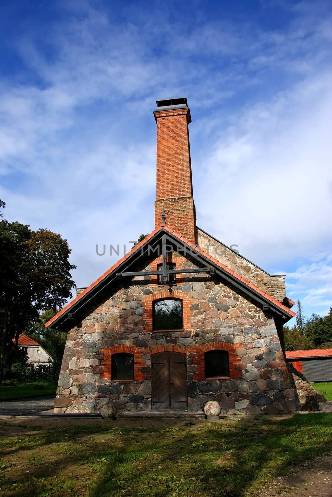 The stone house on a background of the blue sky and clouds