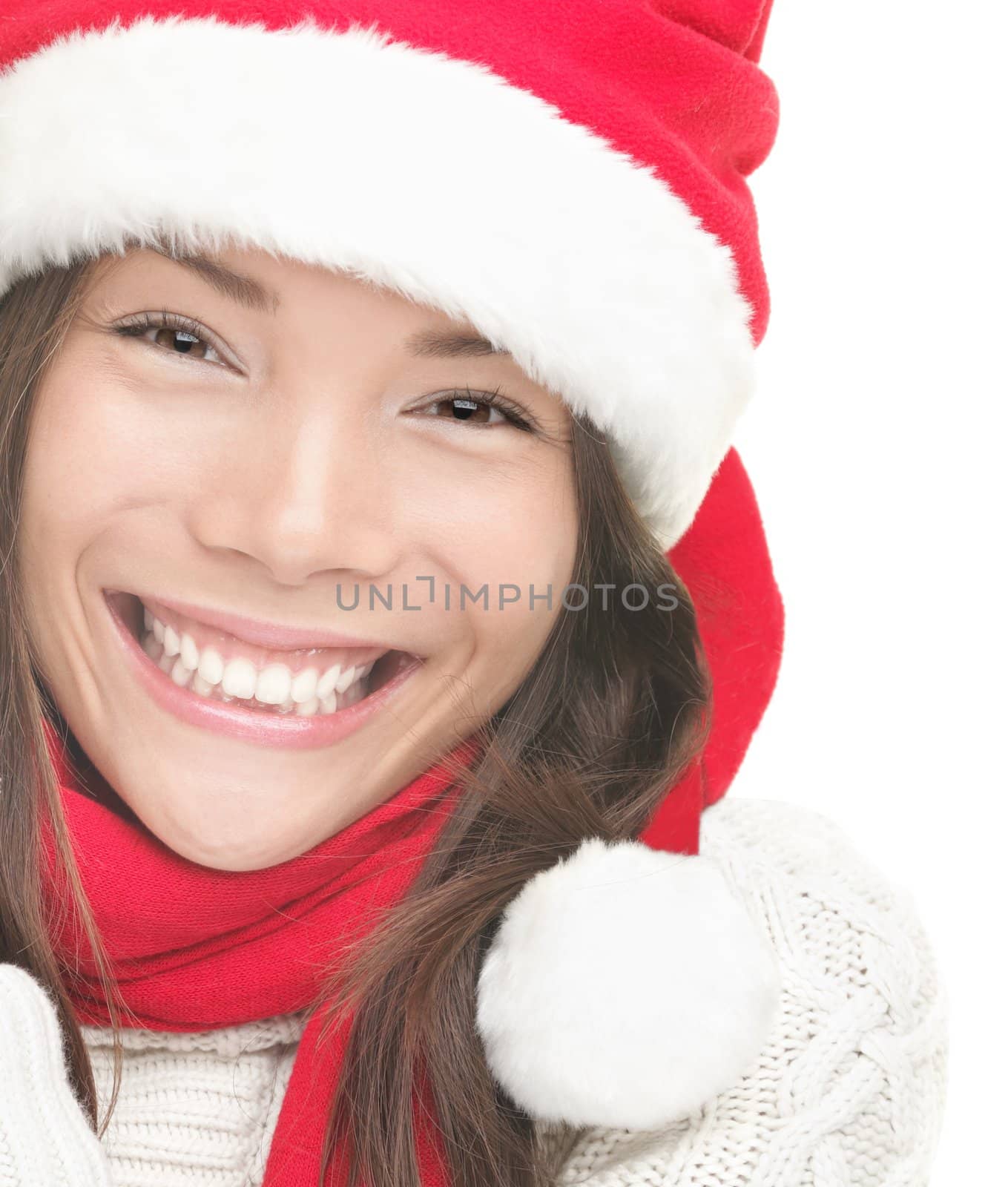 Christmas woman smiling portrait. Young woman wearing Santa hat, sweater and red scarf. Closeup photo of cute Asian / Caucasian woman isolated on white background