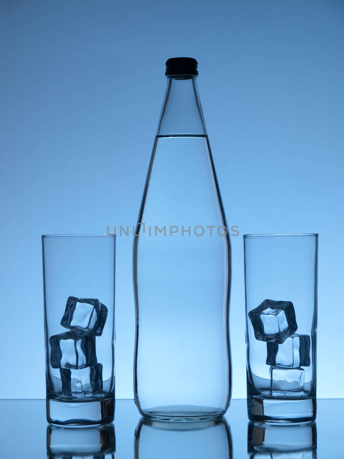 Bottle of water and two glasses with ice on blue