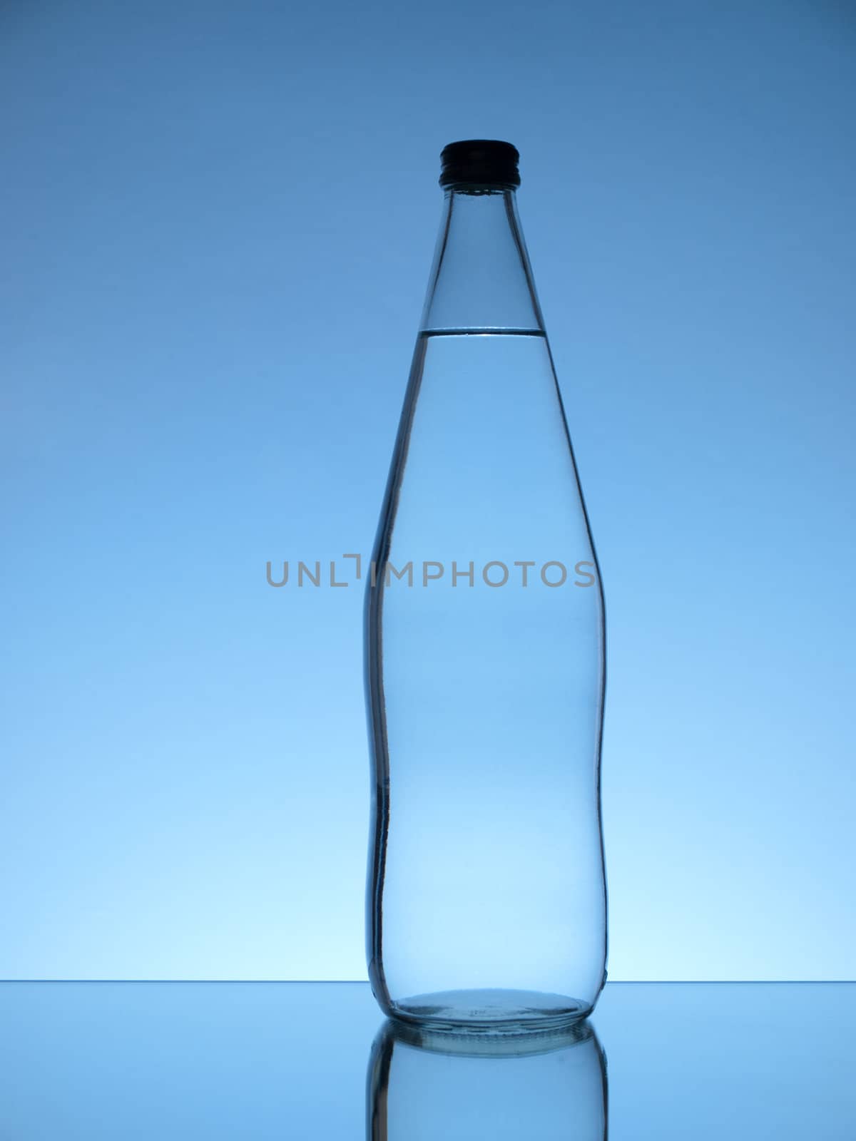 Glass water bottle on blue background