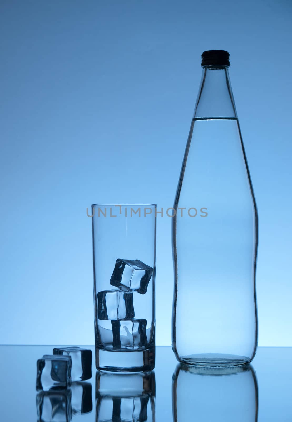Water bottle, glass and ice on blue background