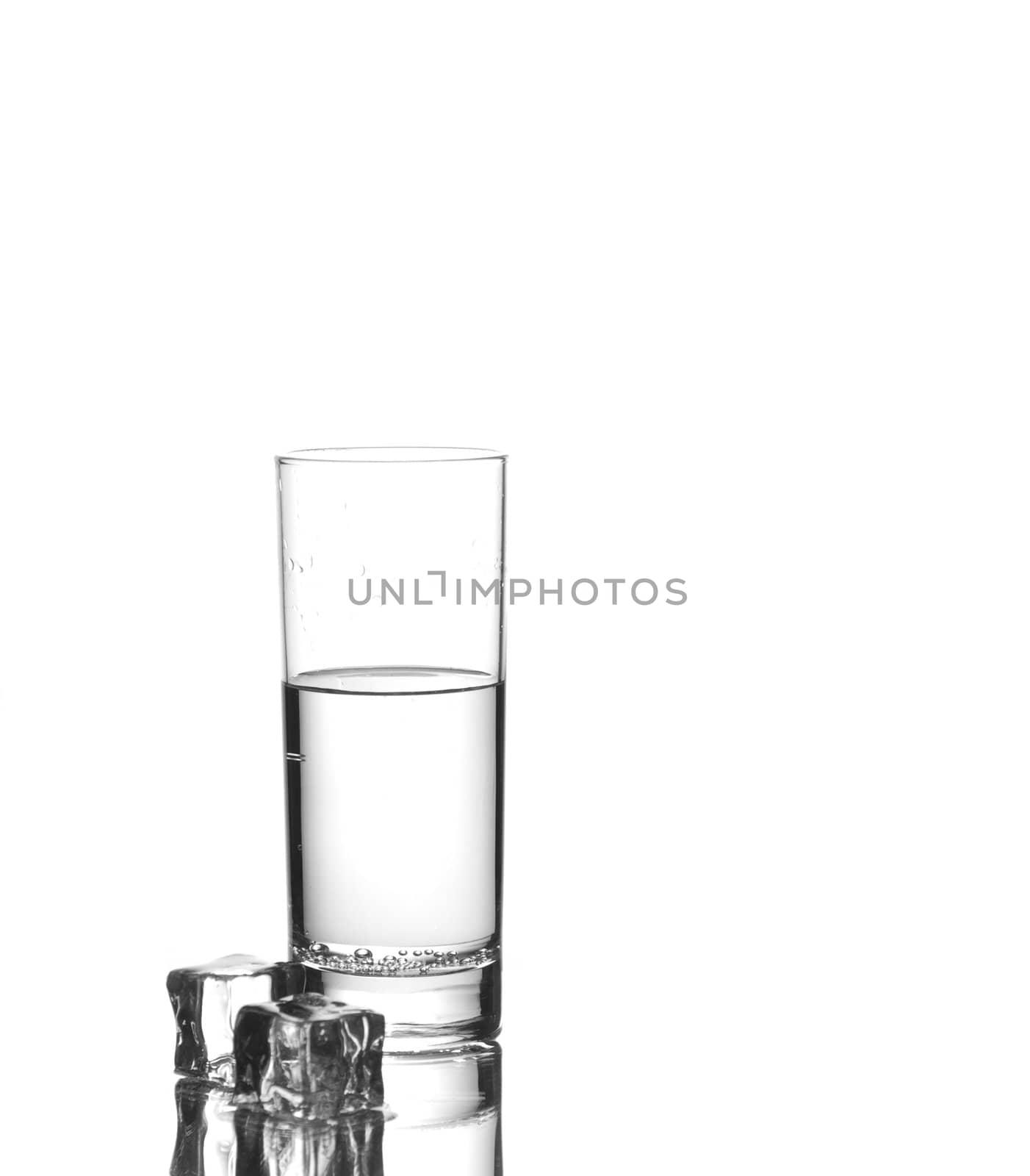 Glass of water with two ice cubes nearby