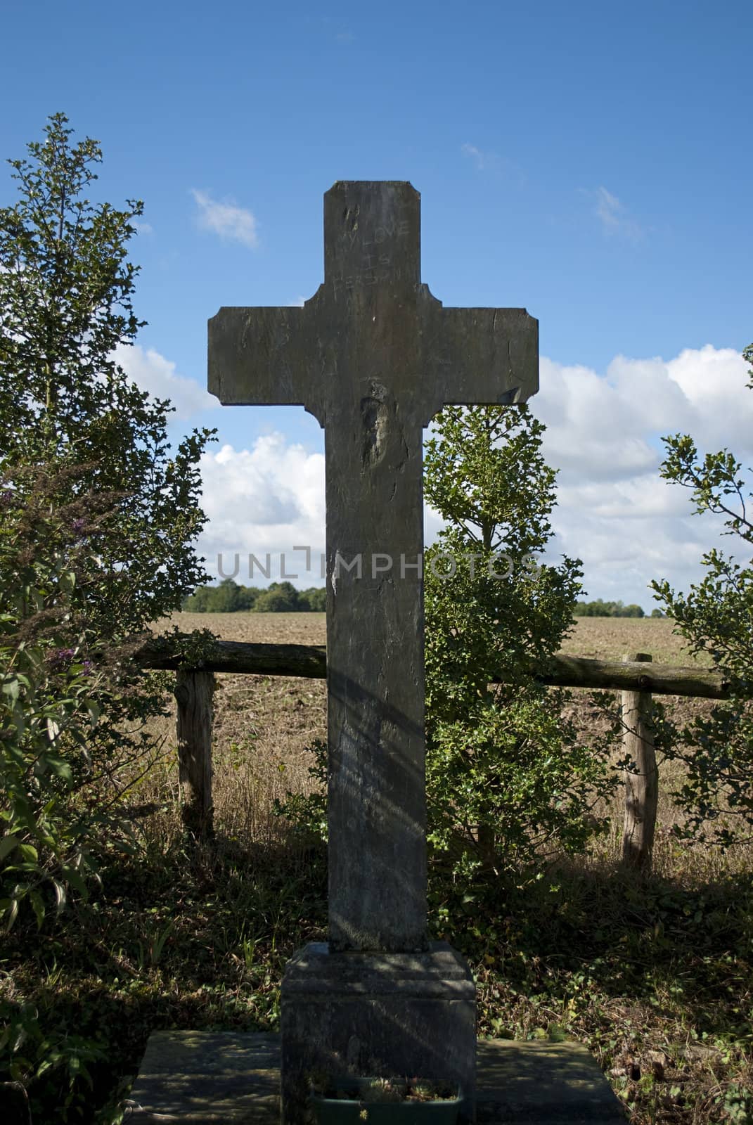 Cross made of stone beside bushes