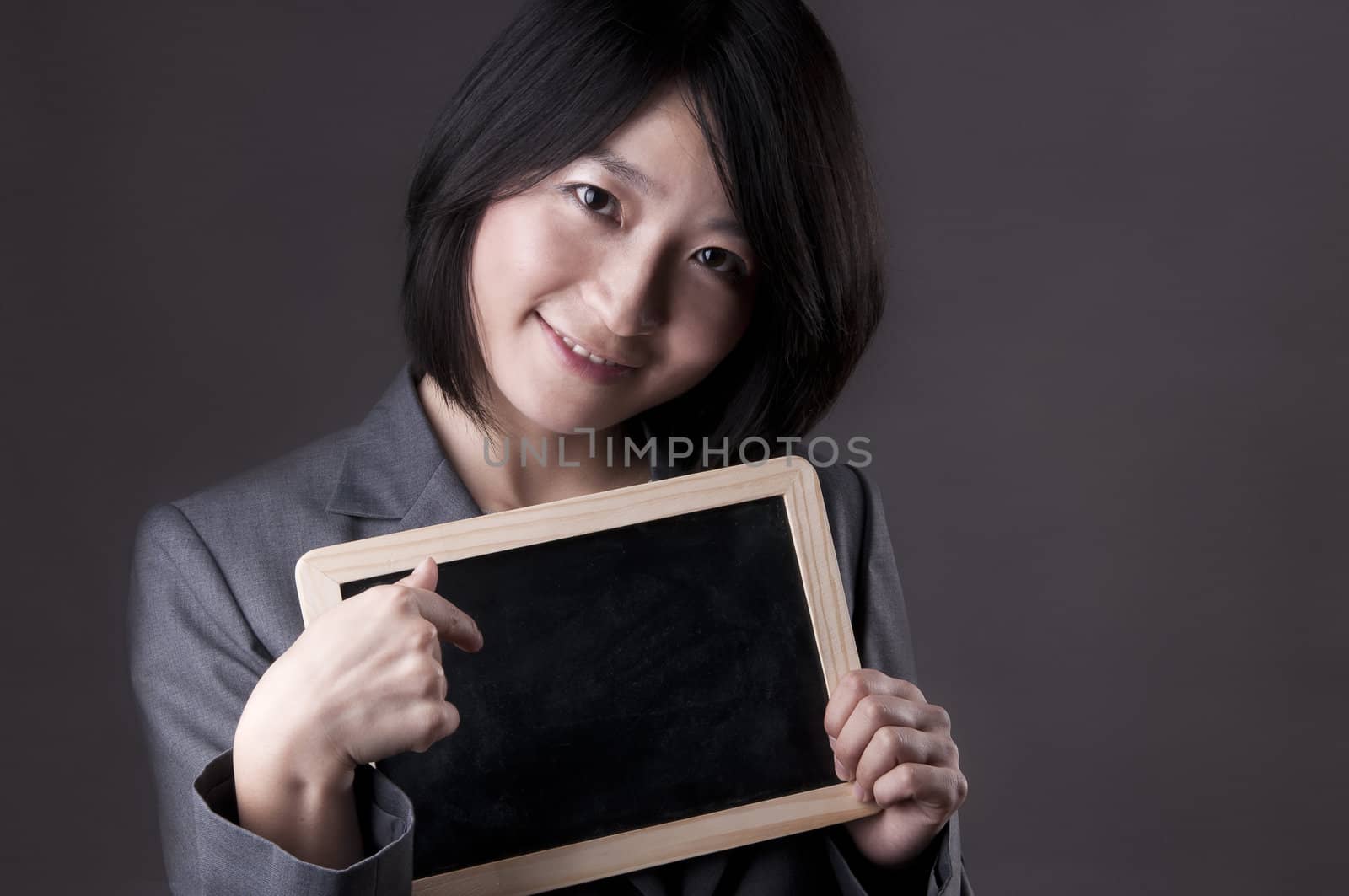 Happy woman in suit pointing to blackboard