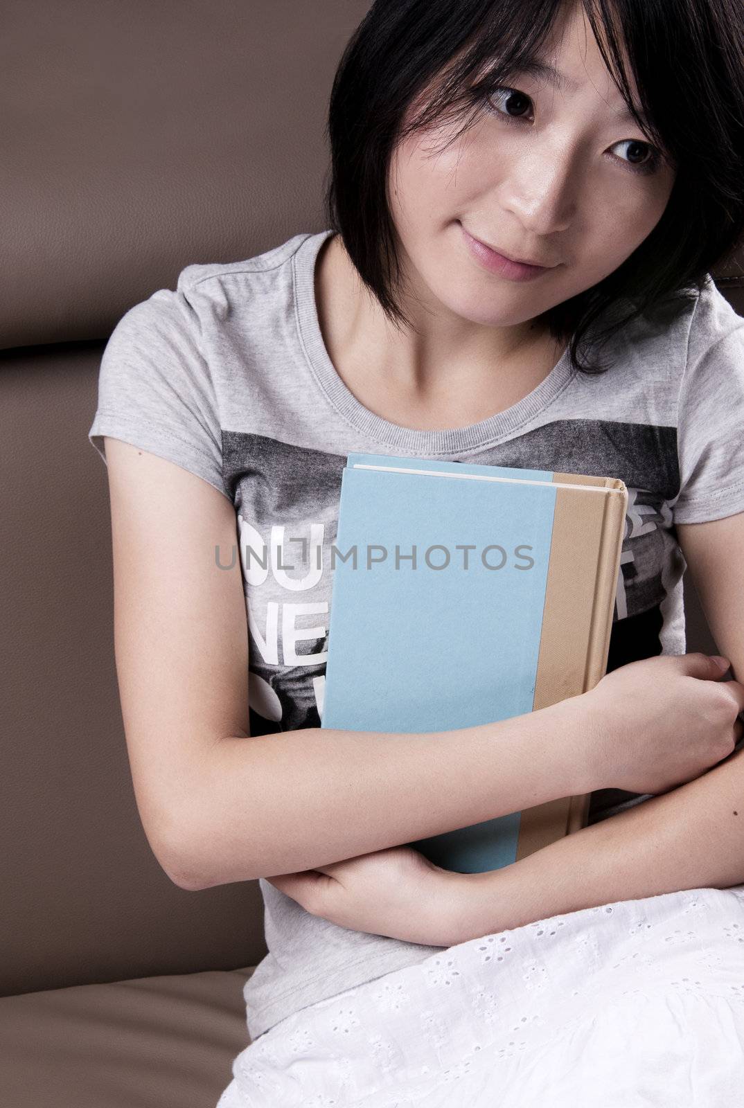Thinking beautiful girl with the book sitting on sofa