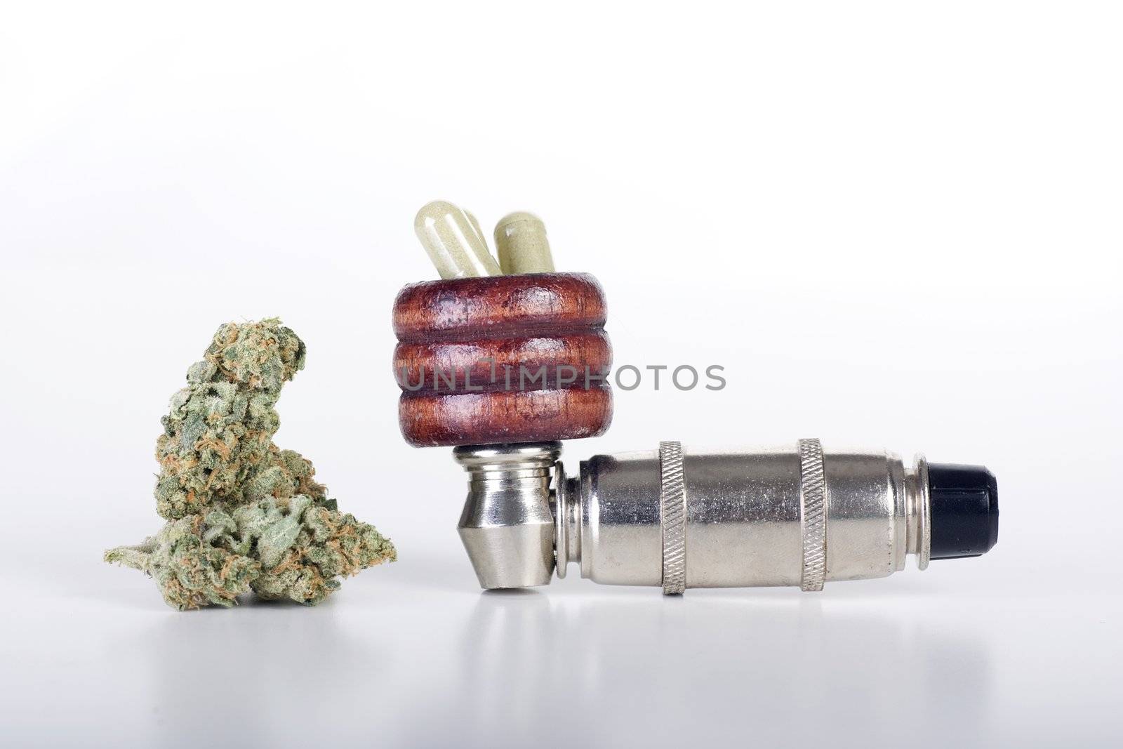 Bud of dried cannabis, pipe and pills.