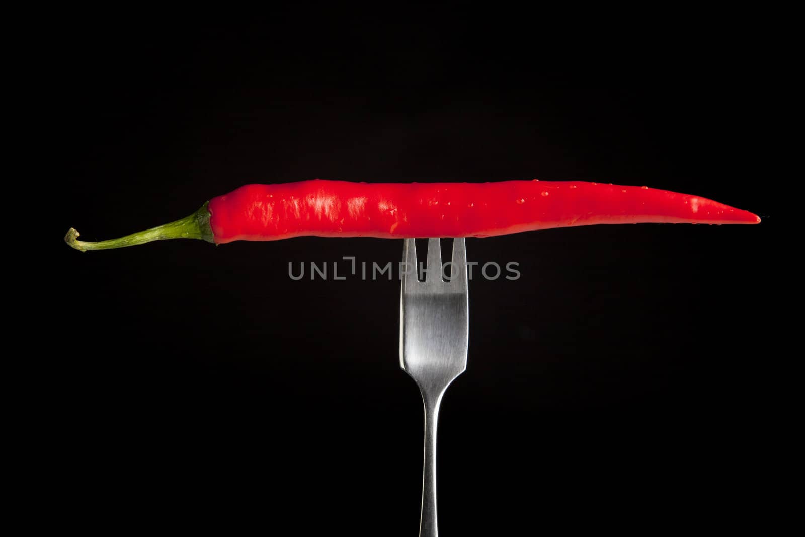 Hot chili pepper on fork with black background